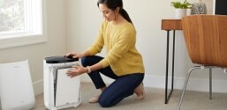A woman changing the filter in a room air purifier.
