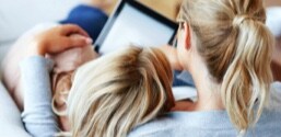 A woman with her arm around her daughter, using a tablet.
